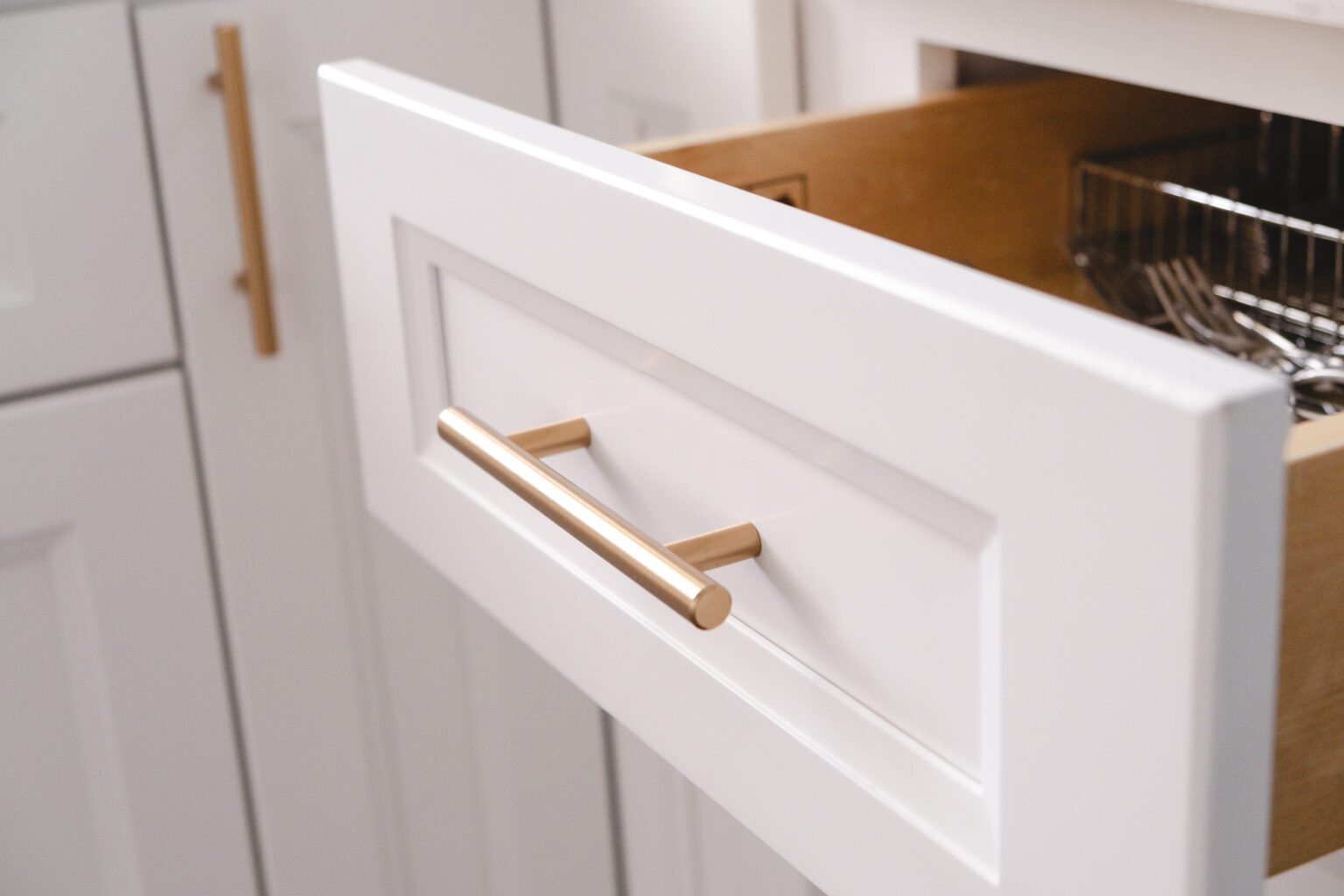 Open white recessed-panel drawer with a long gold-tone pull and interior storage compartments.