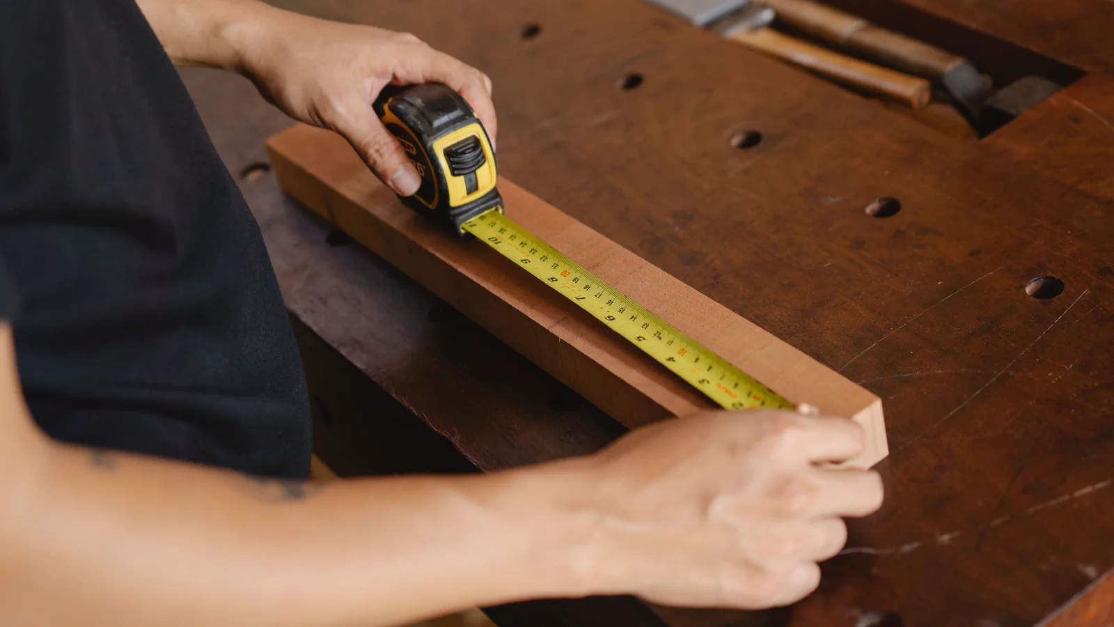 Built to Last Carpenter measuring a wooden component with a tape measure