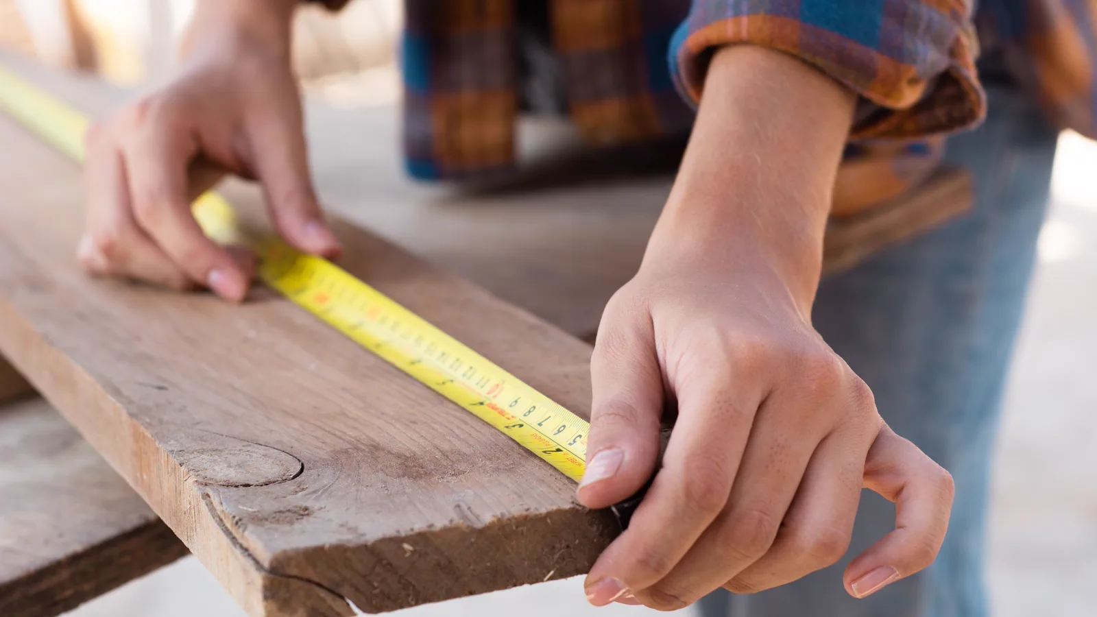 Built to Last Carpenter measuring a wood board with a tape measure for cabinet planning