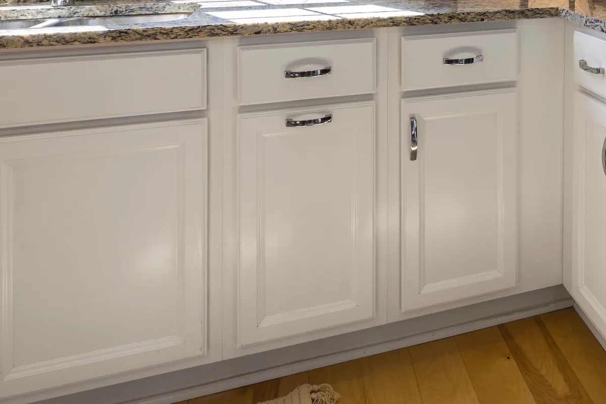 White painted cabinet doors and drawers beneath a stone countertop