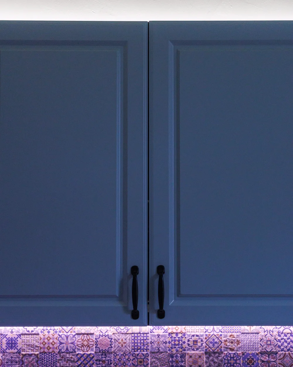 Close view of two blue painted cabinet doors with raised-panel profiles